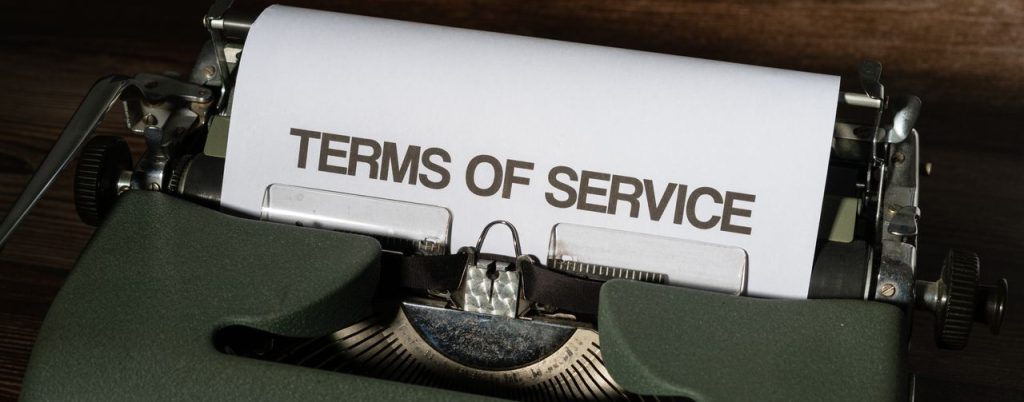 Close-up of a vintage typewriter with 'Terms of Service' paper inside, on a wooden desk.